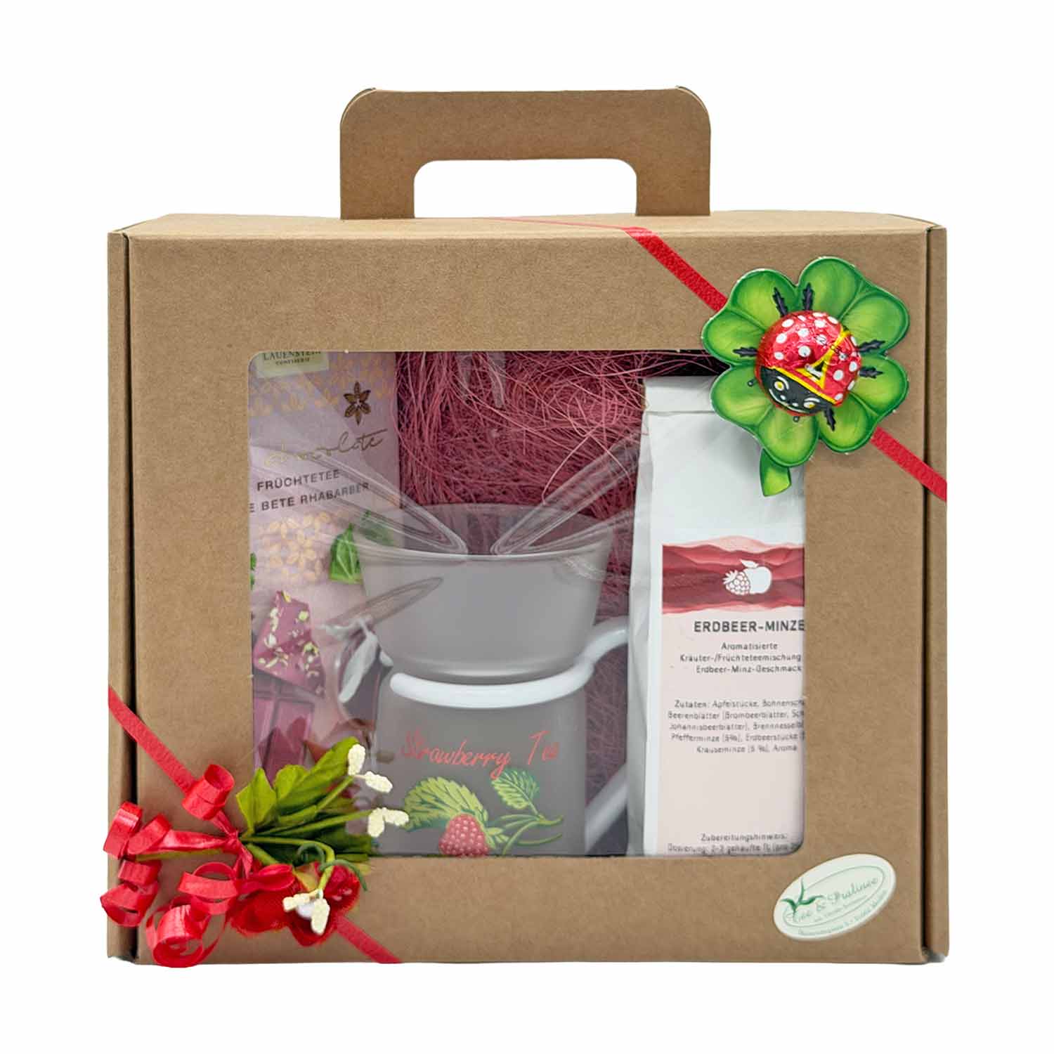 Geschenkbox mit Erdbeertee, einem Glasbecher, Schokolade und einer Marienkäferdekoration, perfekt für Teeliebhaber und zum Verschenken.